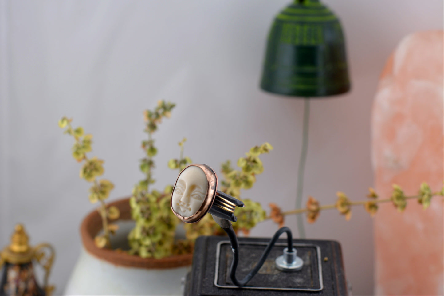 Wise Lady - Triple wire structure, soldered and smoothed for strength and style in a background of basil shrubbery, a green bell, partial pink salt lamp can be seen as well as a perfume bottle in the corner left.